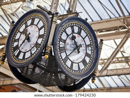 Large decorative clock hanging from a train station roof