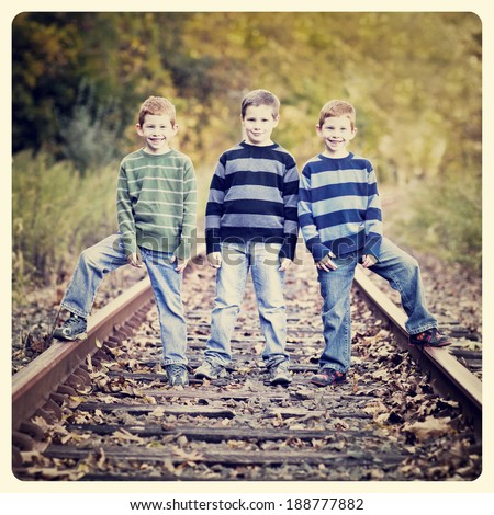 Three brothers standing an old rail tracks with Instagram effect filter
