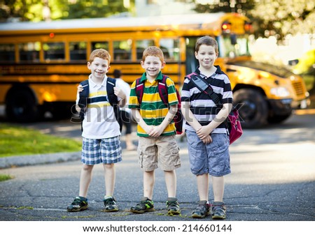 Three boys in front of a school bus