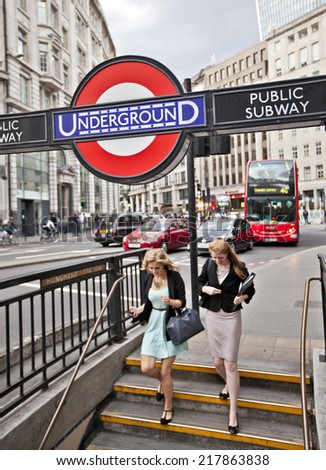 LONDON, UK - AUG 22, 2014: Two women entering the Monument Station London Underground. The London Underground sign is a famous London icon.