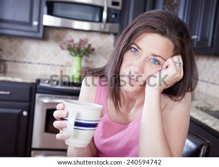 Pretty woman looking unhappy with mug at home