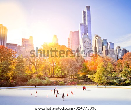Ice skaters having fun in New York Central Park in fall with sun flare