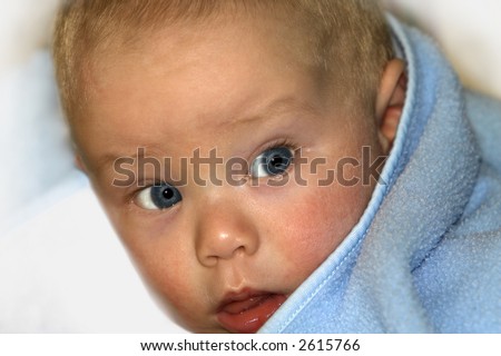 Blue eyed baby looking round with blue blanket