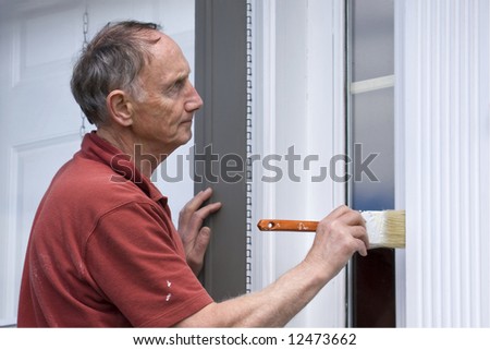 Senior man painting outside of house