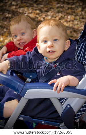 Twin brothers with red hair sitting in stroller outside