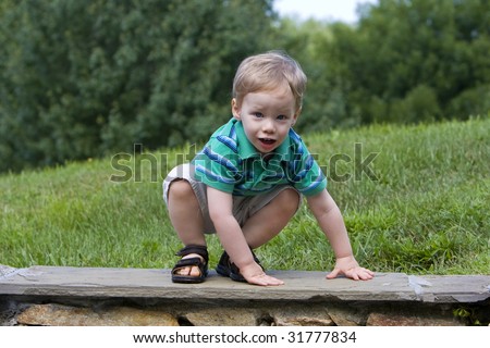 Worried young boy climbing down rock wall