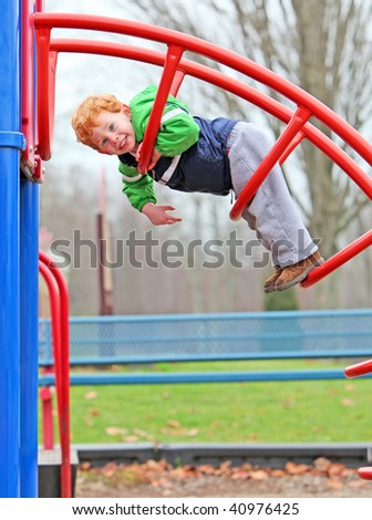 Cute boy climbing on park climbing frame