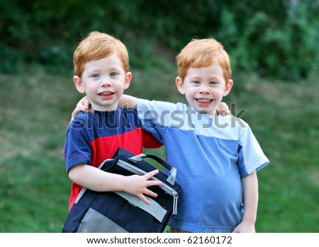 Twin boys with arms around eachother outside portrait