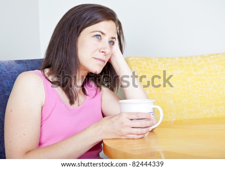 Woman sitting at table drinking coffee alone