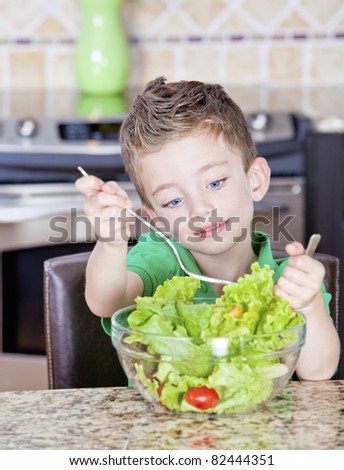 Young boy in kitchen mixing a salad in a bowl