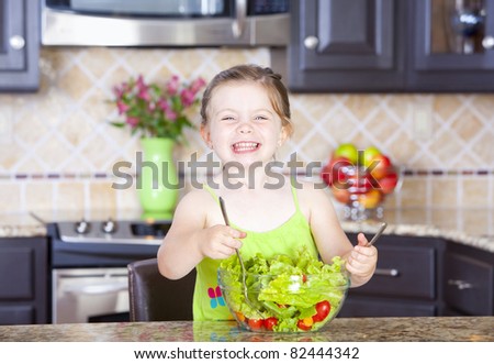 Cute little girl having fun making a salad