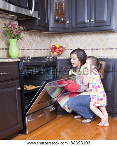 Pretty woman opening oven with a tray of cookies