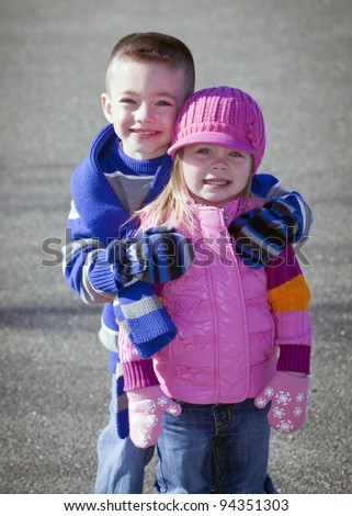 Cute brother and sister in winter hugging outside