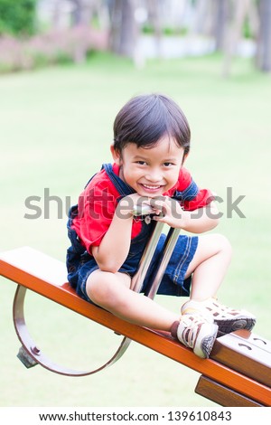 Boy smiling and play at the see-saw in the playground