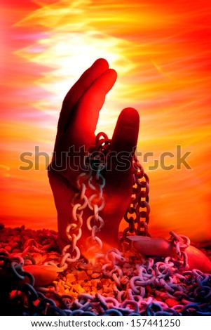 A hand Intertwined with chain and rising from the ground