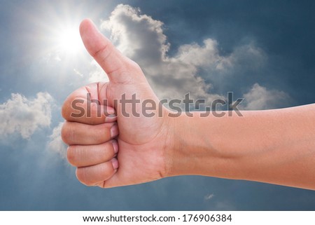 Closeup of man\'s hand shows thumb up in sky