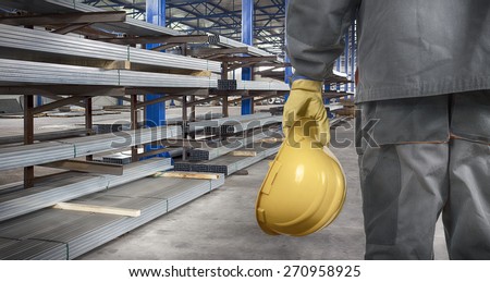 worker with helmet in production hall in front of tin metal profiles