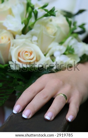 Wedding bouquet. Wedding ring is being placed on the finger.