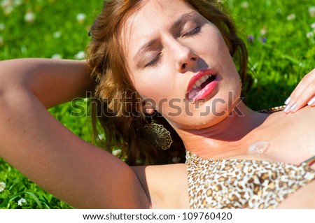 Young girl outdoors holding an ice cube in her mouth. Cold drops fall on her body. Heat concept.
