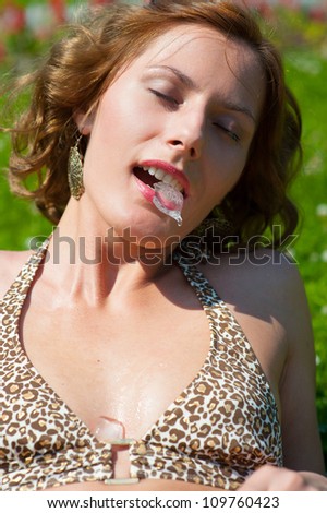 Young girl outdoors holding an ice cube in her mouth. Cold drops fall on her body. Heat concept.