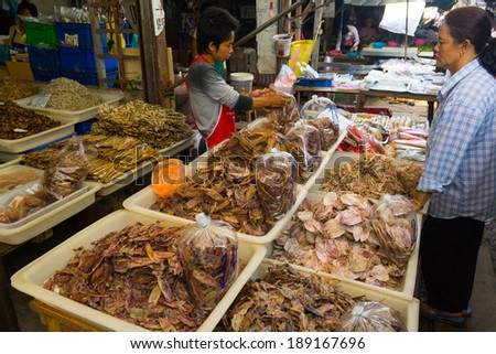 MAEKLONG, THAILAND - MARCH 24: Vendor sells dried local fishery production on March 24, 2014 in famous Maeklong Railway Market also known as Talad Rom Hub or Umbrella Pulldown Market