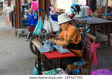MAEKLONG, THAILAND - MARCH 24: Tailor repairing clothes on March 24, 2014 in famous Maeklong Railway Market also known as Talad Rom Hub or Umbrella Pulldown Market