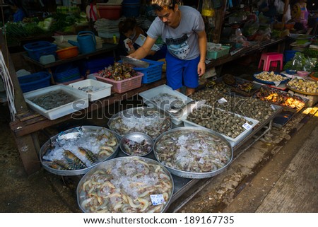 MAEKLONG, THAILAND - MARCH 24: Vendor sells fresh local fishery production on March 24, 2014 in famous Maeklong Railway Market also known as Talad Rom Hub or Umbrella Pulldown Market