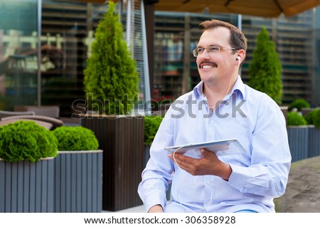 Middle age businessman listen music from tablet pc outdoors