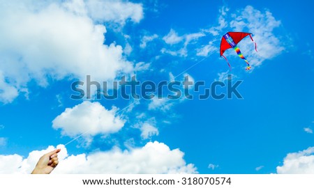 Hand holding kite in the cloudy sky. Focus to the kite