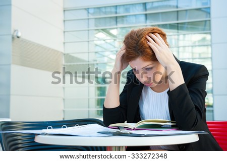Frustrated and tired business woman sitting in modern background