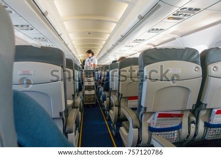 Steward offers food and drinks to economy class passengers on the plane