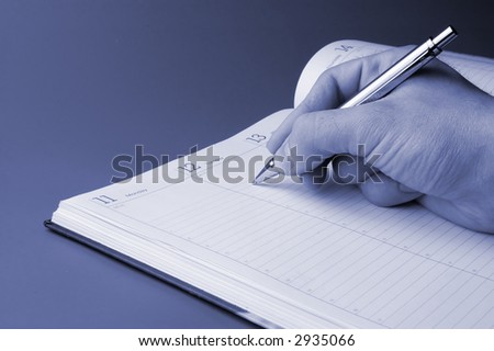 Man holding pen and writing in weekly planner