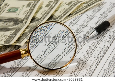 Looking through magnifying glass to the dollars banknotes and financial report