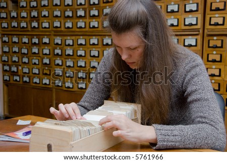 Young woman searching file in the library card index.