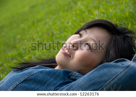 Dreams in the grass - young attractive woman  relaxes in the park
