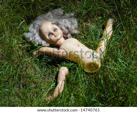 Partitioned blonde doll with blue eyes lie in the grass