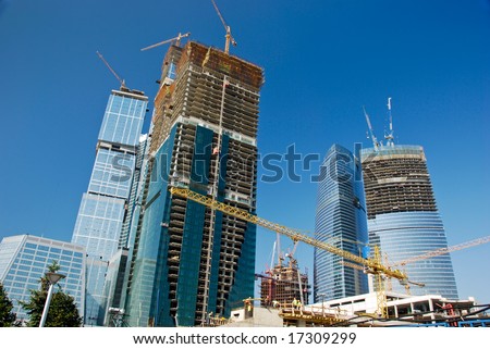 Sky-scrapers construction. Cranes and buildings over blue sky.