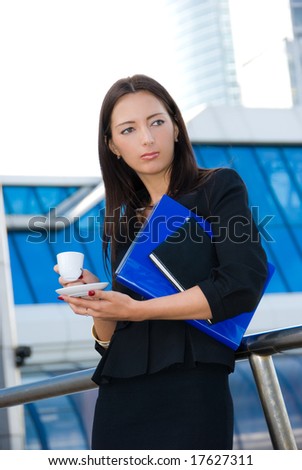 Business woman drinks a coffee outdoors in modern downtown