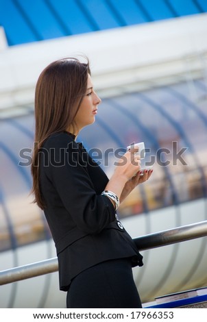 Business woman drinks a coffee outdoors in modern downtown