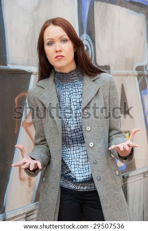 Aggressive woman stands near wall with graffiti
