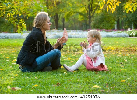 Mother and daughter sit and play in the park