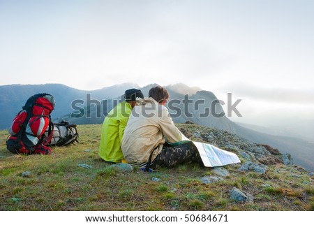 Hikers sit on the peak and exploring the map
