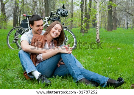 Young couple resting in a park, bicycles on background