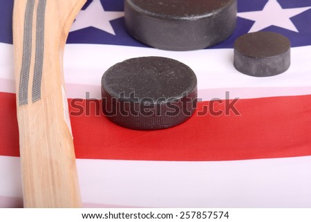 Hockey equipment including a stick and puck on an American flag to infer a patriotic American sport.