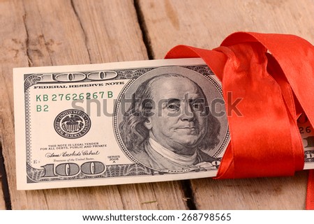 american money dollars and red ribbon on wooden plate, business concept
