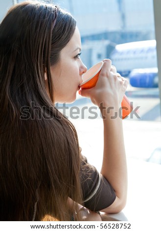 Young woman is drinking coffee in airport