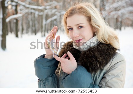 a smiling woman with a figure of a crystal angel is in the winter forrest