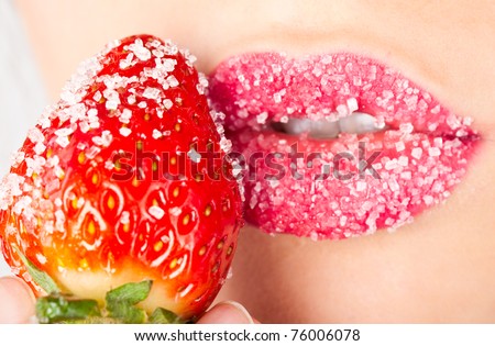 Young woman's mouth with red strawberry covered with sugar