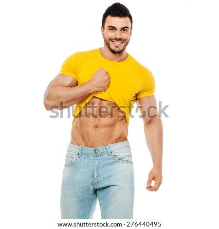 Bodybuilder or personal trainer pulling his t-shirt up and smiling at the camera on white background