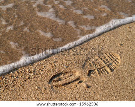 Shoe-print in wet sand with wave